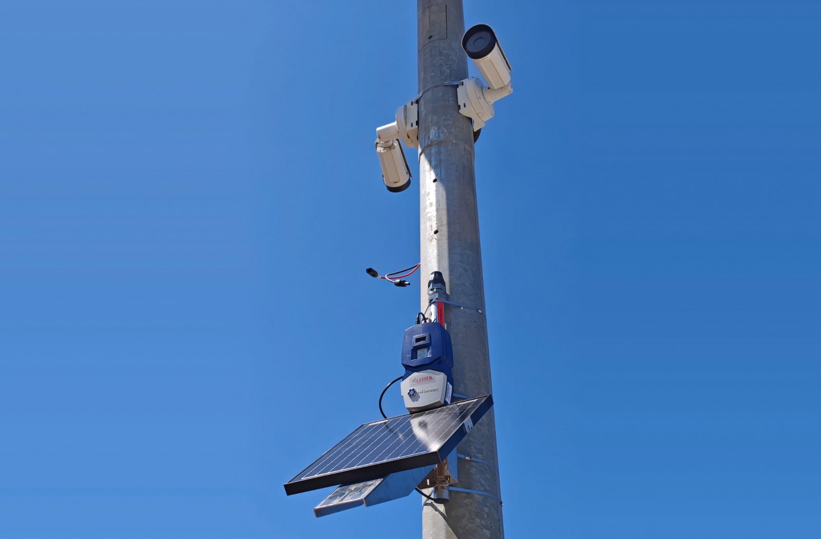 SafeForest Shield pole: PTZ cameras on top, N5 Sensors IoT node and a solar panel below, against a clear sky
