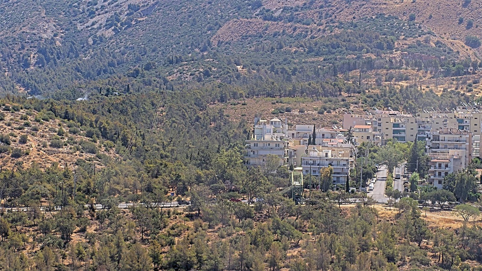 Camera frame: smoke near houses at the wildland–urban interface, marked by the AI
